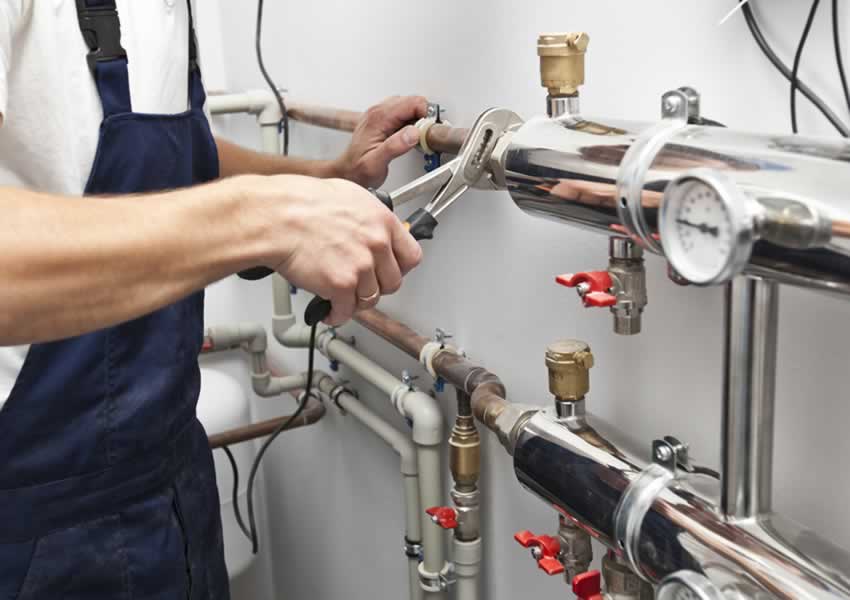 plumber adjusts central heating pipework