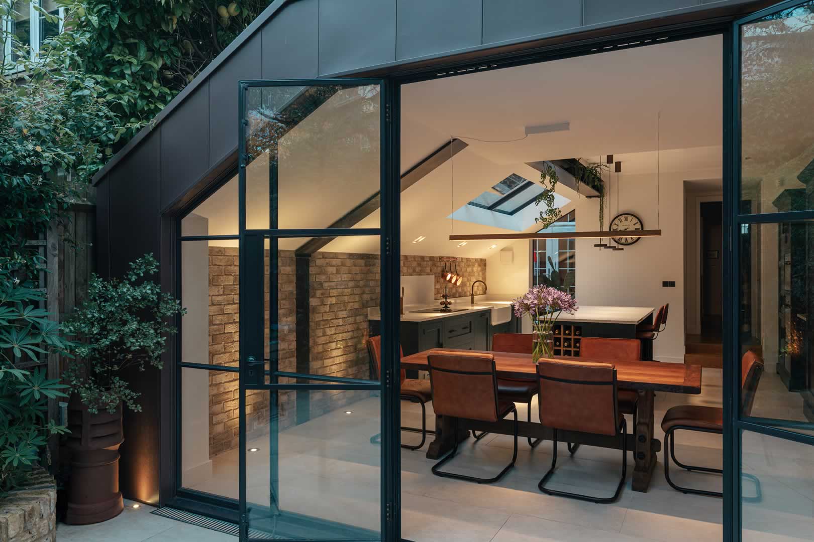 parsons green house view from the garden into the new kitchen via the fully-glazed patio doors and showiung the copper finish on the gable end trim of the new kitchene extension